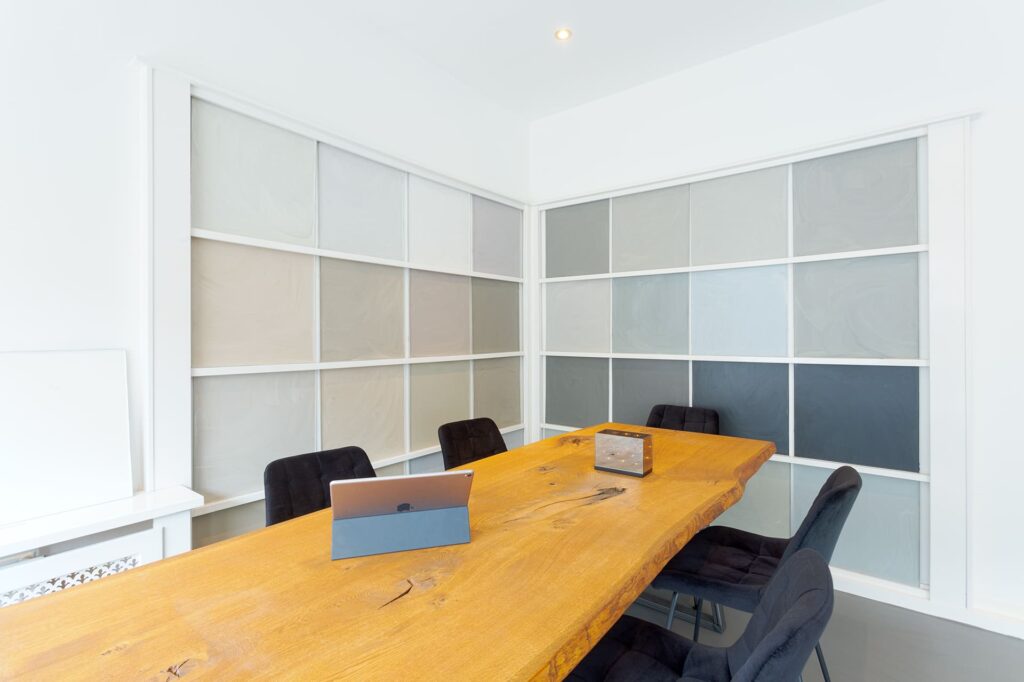 Moderne conferentieruimte met een houten tafel en zachte pastelkleurige gietvloer kleurstalen aan de muur, weerspiegelend de kleurentrends van 2024.