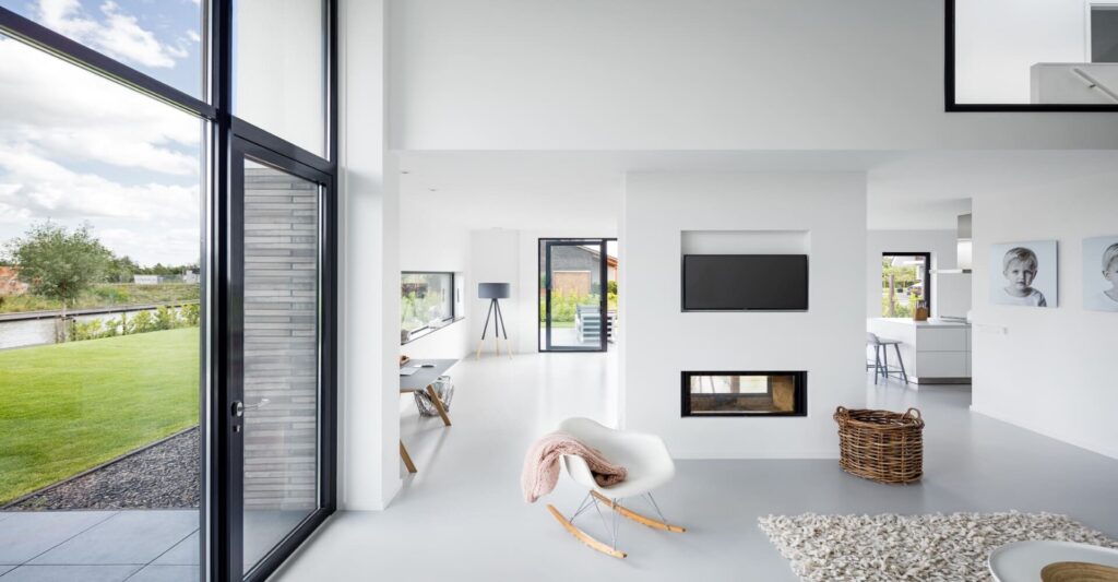 Ruim en licht interieur van een moderne woonkamer met een naadloze, stijlvolle witte gietvloer, die bijdraagt aan de realisatie van een woondroom met een strak en hedendaags design.