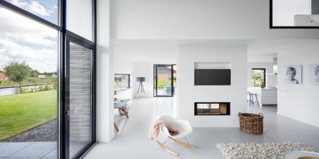 Ruim en licht interieur van een moderne woonkamer met een naadloze, stijlvolle witte gietvloer, die bijdraagt aan de realisatie van een woondroom met een strak en hedendaags design.